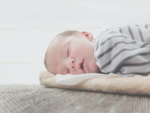Slyngevugge baby sover på tæppe